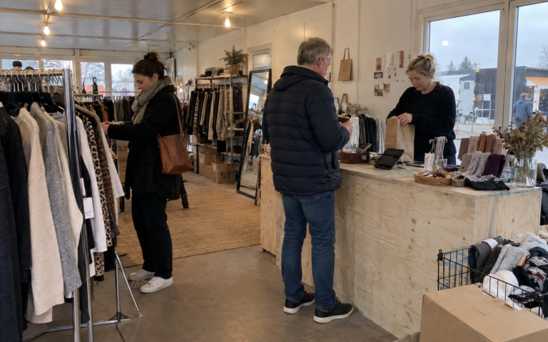 Kunder besøger en midlertidig butik med tøj og varer på udstilling.