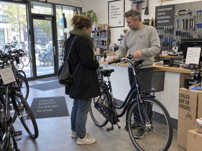 Illustration af en medarbejder, der hjælper en kunde i en cykelbutik.